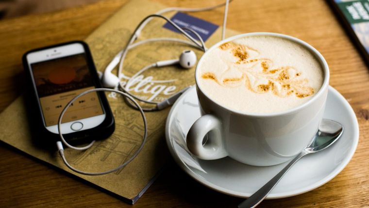 Cup of coffee and mobile phone with earphones
