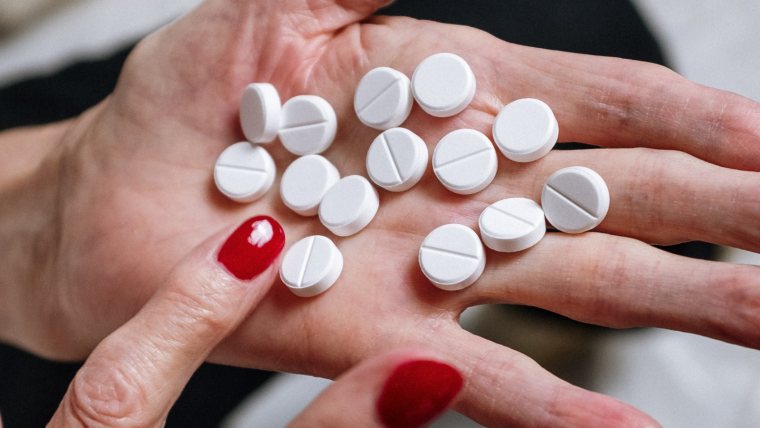 A woman's hand filled with round white pills.